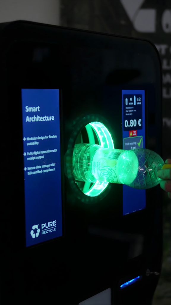 A close-up of the Pure RVM 5 bottle intake process, showing the illuminated green sensor ring and a clear plastic bottle being inserted for fast recycling